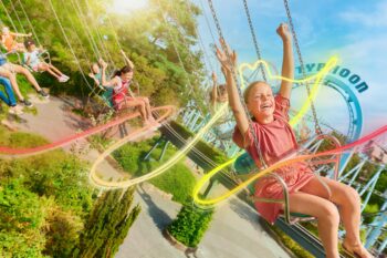 Enfants s'amusant sur manèges dans un parc d'attractions.