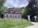 Maison en brique avec jardin et clôture métallique.