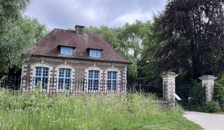 Maison en brique avec jardin et clôture métallique.