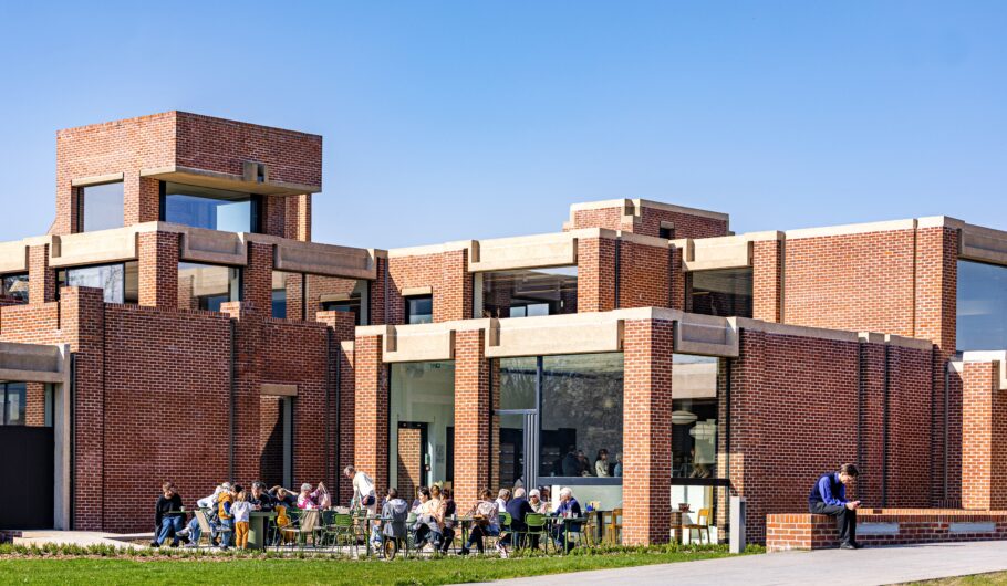 Bâtiment en briques avec personnes assises dehors.