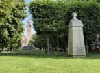 Statue et église dans un parc verdoyant.