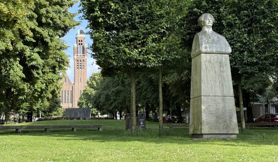 Statue et église dans un parc verdoyant.