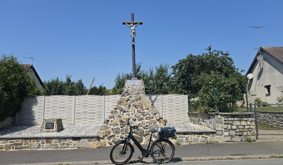 Vélo devant calvaire en pierre sous ciel bleu