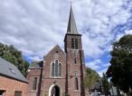 Église en briques avec haut clocher sous ciel nuageux