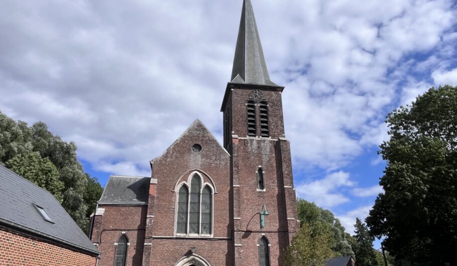 Église en briques avec haut clocher sous ciel nuageux