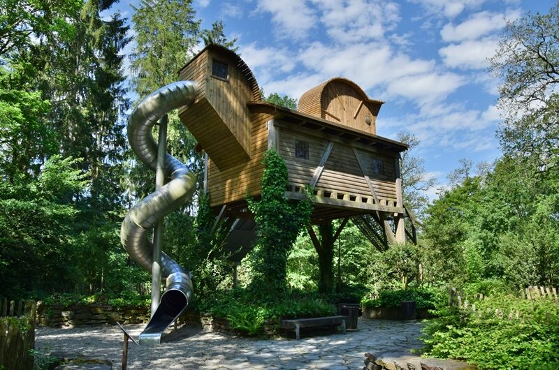 Cabane perchée avec toboggan métallique dans un jardin