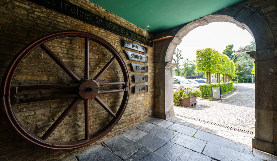 Grande roue de forge sous une arche en pierre
