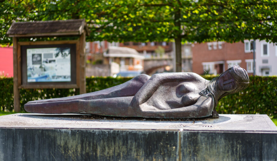 Sculpture en bronze d’une femme allongée dans un jardin